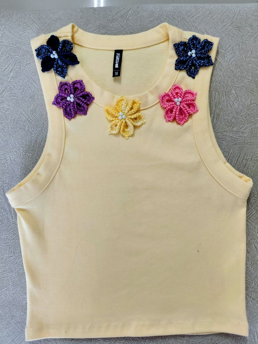 Top amarillo pastel con cinco flores de crochet y perlas